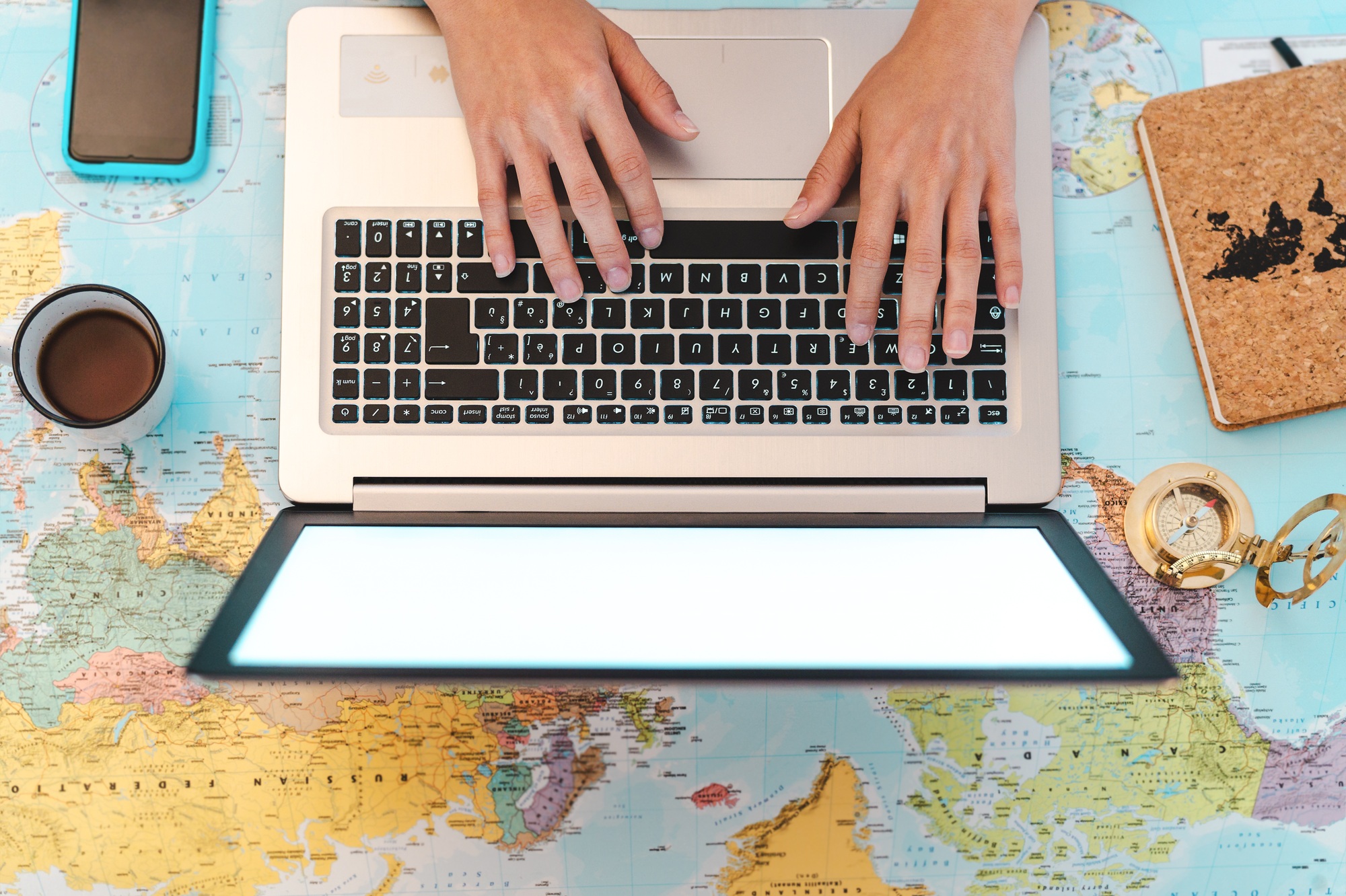 Top view female hands using laptop on world map booking next travel destinations